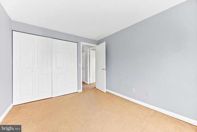 unfurnished bedroom with light colored carpet and a closet