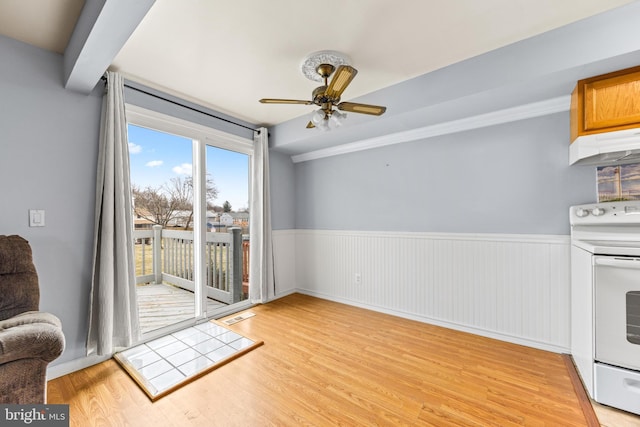 interior space featuring ceiling fan, white electric range oven, light hardwood / wood-style floors, and beam ceiling