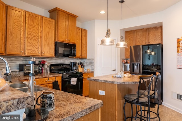 kitchen featuring a kitchen island, pendant lighting, tasteful backsplash, a breakfast bar area, and black appliances