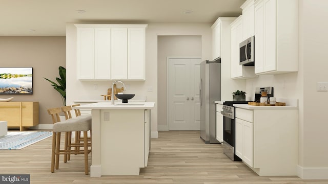 kitchen with appliances with stainless steel finishes, white cabinets, a kitchen bar, and light hardwood / wood-style flooring