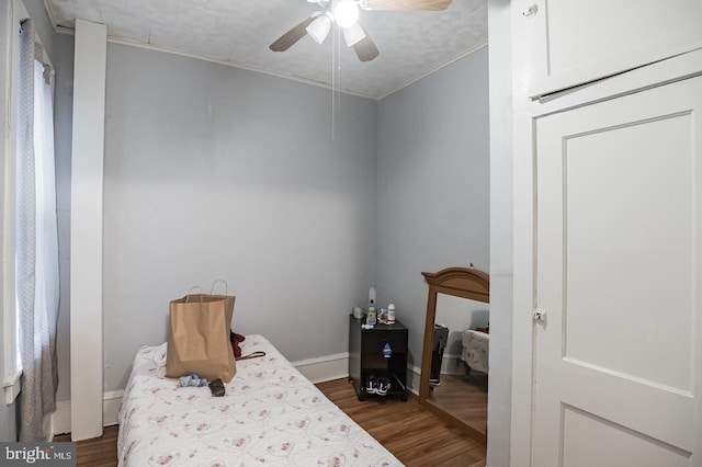 bedroom with crown molding, dark wood-type flooring, and ceiling fan