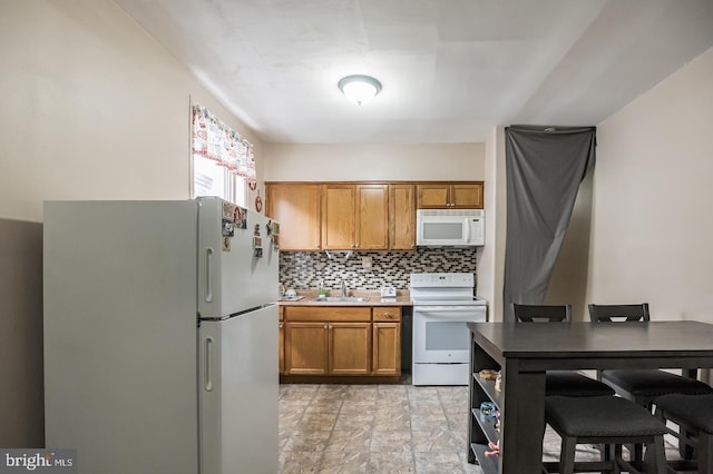 kitchen featuring sink, backsplash, and white appliances