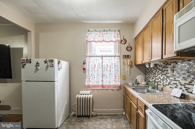 kitchen featuring sink, white appliances, radiator heating unit, and decorative backsplash