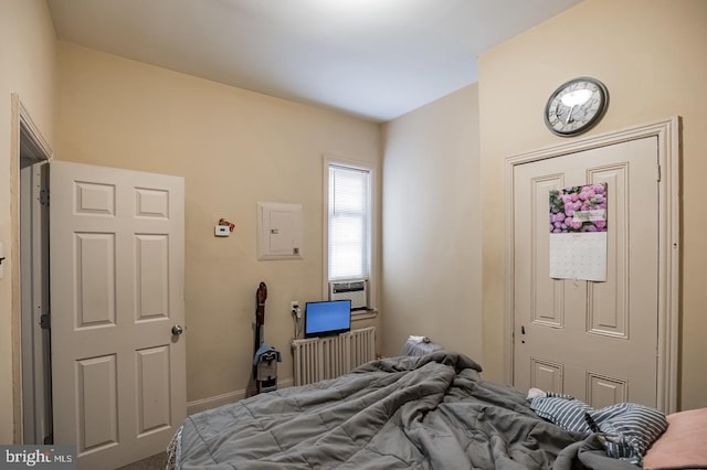 bedroom with cooling unit, radiator heating unit, and electric panel