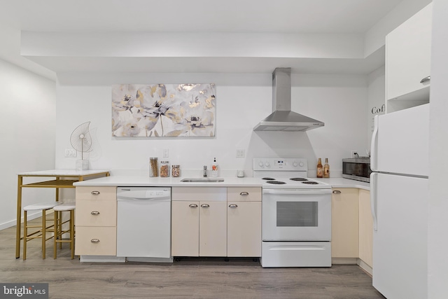 kitchen featuring sink, wall chimney range hood, white appliances, and light hardwood / wood-style floors