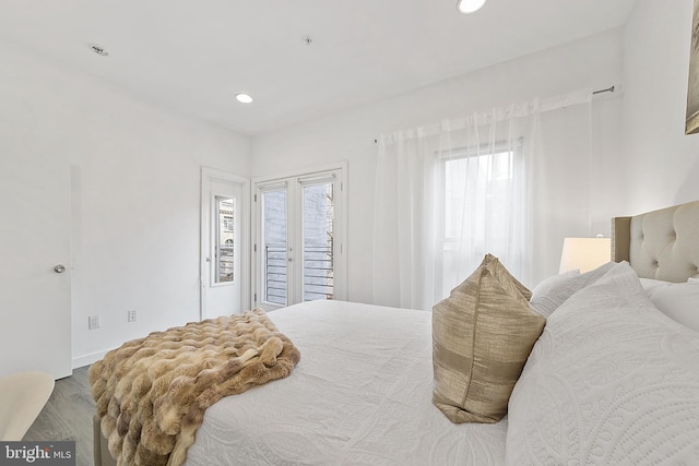 bedroom with wood-type flooring, access to exterior, and multiple windows