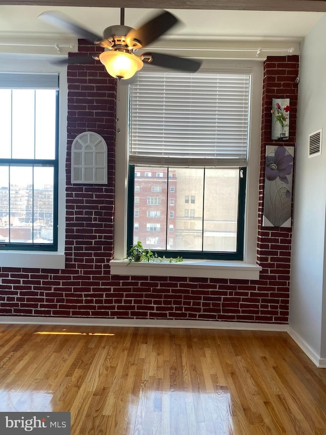 interior space featuring ceiling fan, brick wall, and light wood-type flooring