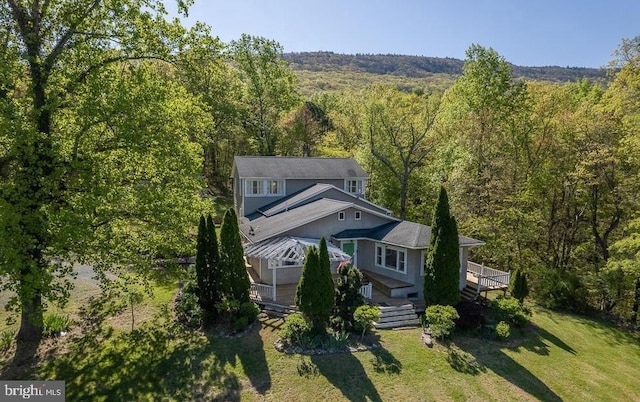 exterior space with a front lawn, a wooded view, and a wooden deck