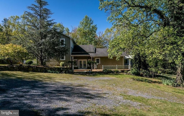 back of property with driveway, french doors, a lawn, and a deck