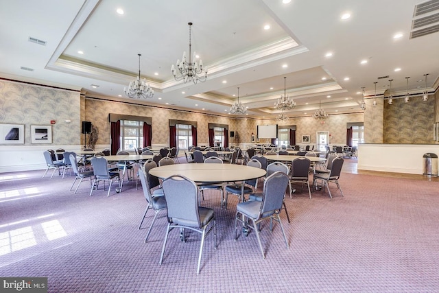 carpeted dining area featuring a raised ceiling, ornamental molding, and an inviting chandelier