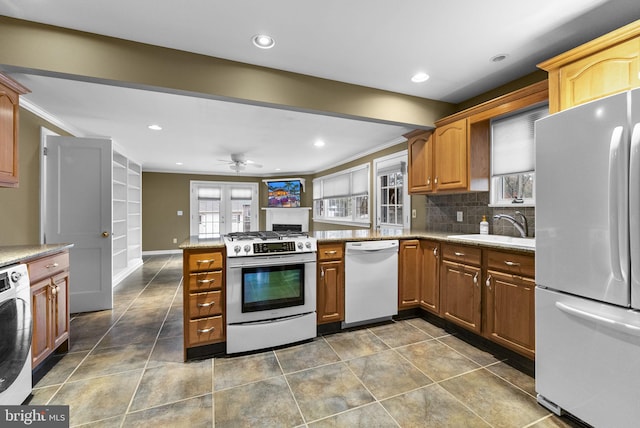 kitchen with kitchen peninsula, sink, washer / clothes dryer, white appliances, and crown molding