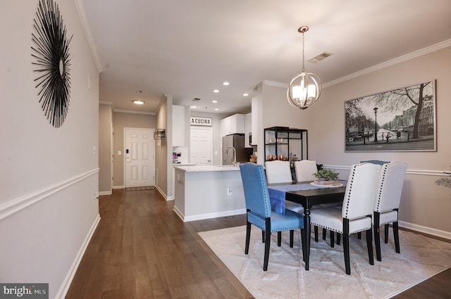 dining room featuring dark hardwood / wood-style flooring, a notable chandelier, ornamental molding, and sink