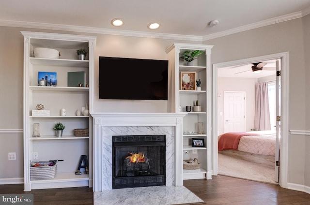 living room with dark hardwood / wood-style flooring, built in shelves, a high end fireplace, and ornamental molding