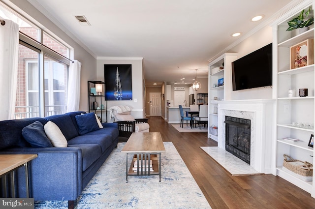 living room with a premium fireplace, ornamental molding, dark hardwood / wood-style floors, and built in shelves