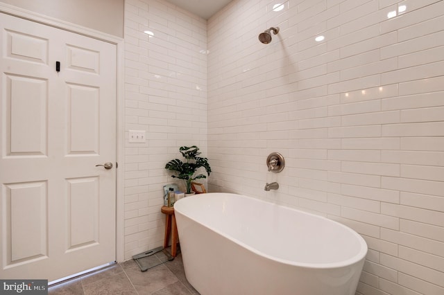 bathroom with tile patterned flooring, a bath, and tile walls