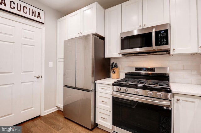 kitchen with tasteful backsplash, stainless steel appliances, light stone countertops, and white cabinets