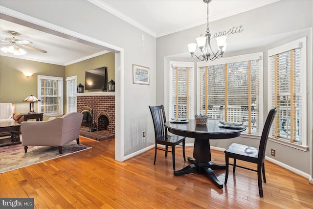 dining area with a brick fireplace, crown molding, plenty of natural light, and light hardwood / wood-style floors