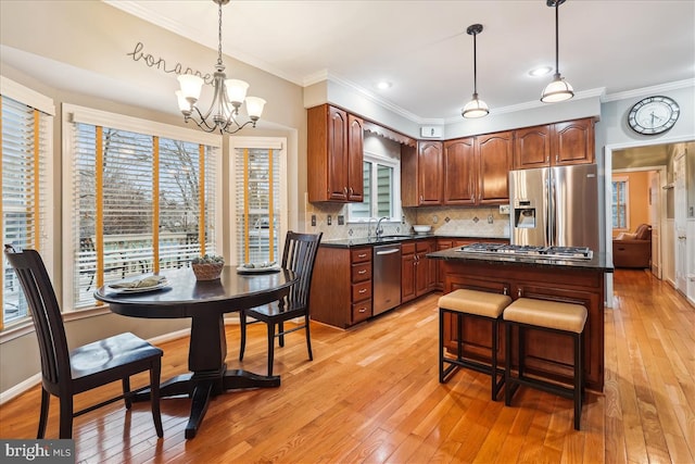 kitchen featuring appliances with stainless steel finishes, decorative light fixtures, sink, a chandelier, and a center island