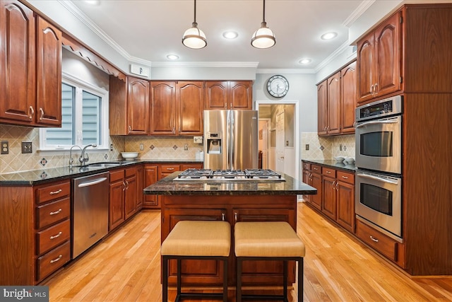 kitchen with sink, a center island, hanging light fixtures, a kitchen breakfast bar, and stainless steel appliances