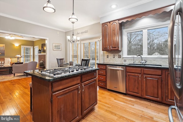 kitchen featuring pendant lighting, a kitchen island, light hardwood / wood-style flooring, and appliances with stainless steel finishes