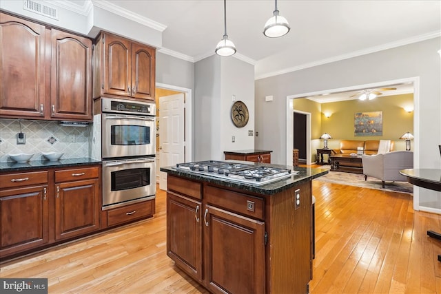 kitchen featuring dark stone countertops, appliances with stainless steel finishes, pendant lighting, and light wood-type flooring