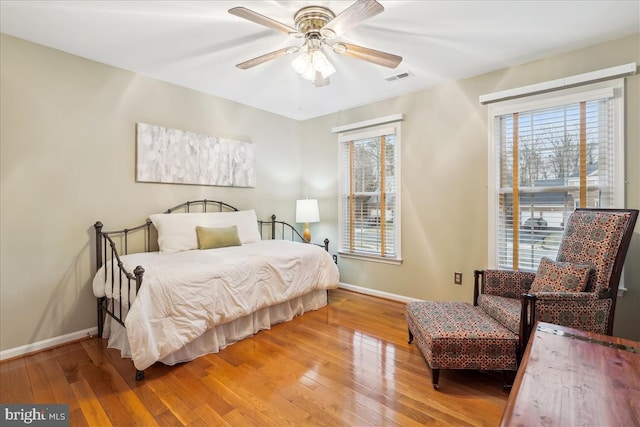 bedroom with multiple windows, hardwood / wood-style floors, and ceiling fan