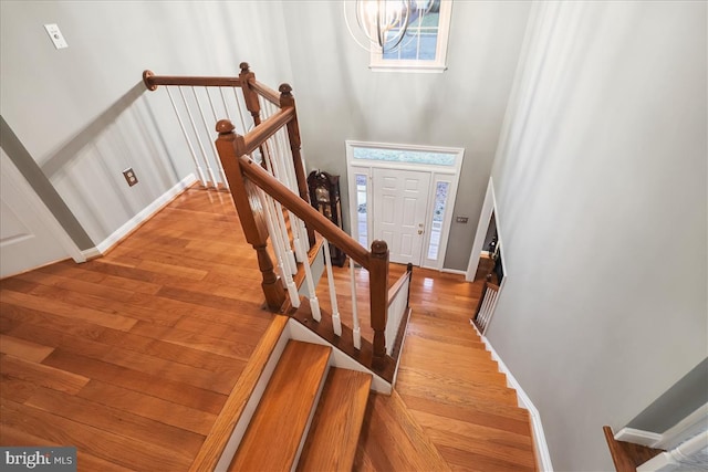 staircase featuring a high ceiling, hardwood / wood-style floors, and a notable chandelier