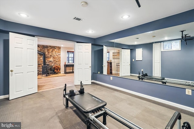 exercise area featuring a healthy amount of sunlight and a wood stove