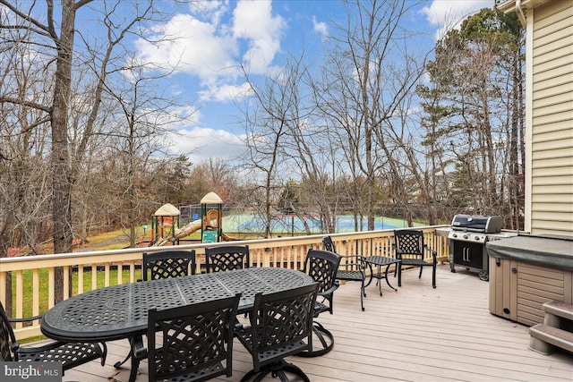 wooden deck with a water view, area for grilling, and a playground