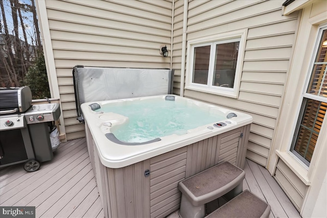 wooden deck with a hot tub and a grill