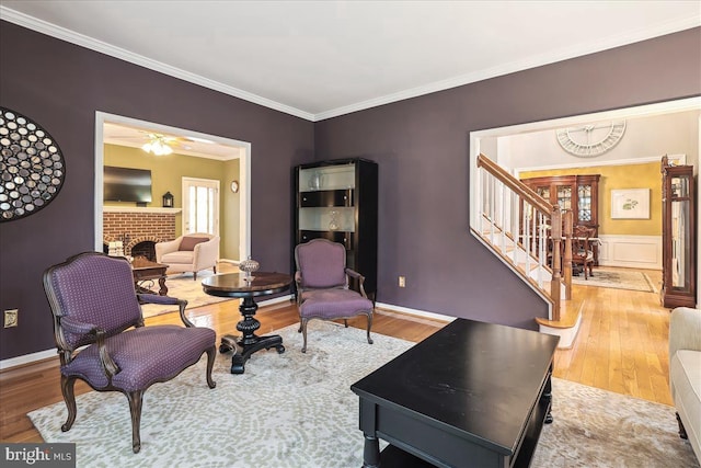 living room with hardwood / wood-style flooring, ornamental molding, and a fireplace