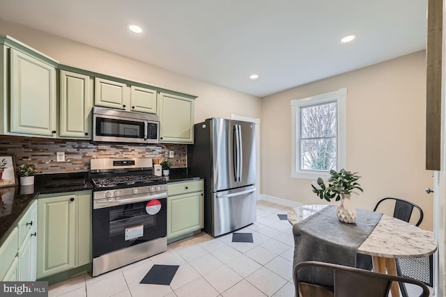 kitchen with light tile patterned floors, stainless steel appliances, a kitchen breakfast bar, green cabinetry, and decorative backsplash