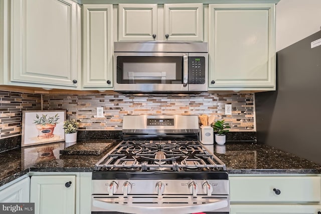 kitchen featuring white cabinetry, tasteful backsplash, stainless steel appliances, and dark stone countertops