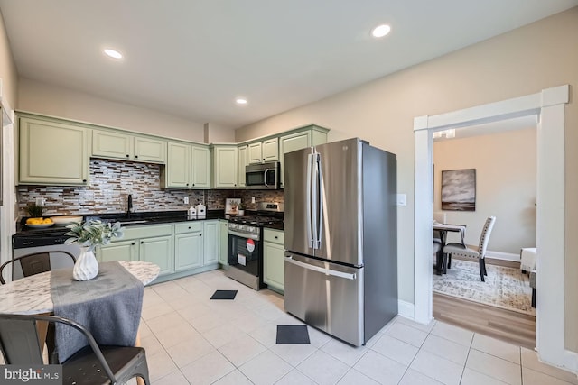 kitchen with sink, green cabinets, backsplash, stainless steel appliances, and light tile patterned flooring