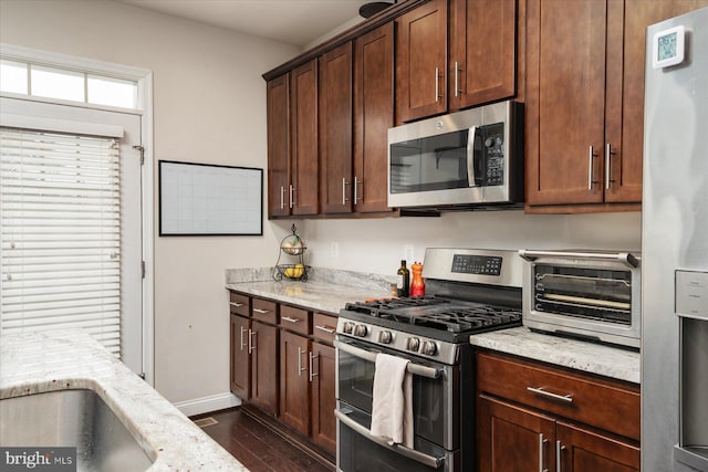 kitchen with stainless steel appliances, dark hardwood / wood-style flooring, and light stone countertops