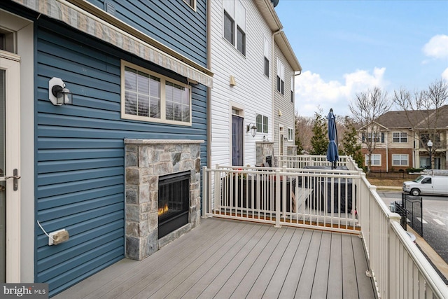 wooden deck featuring an outdoor stone fireplace