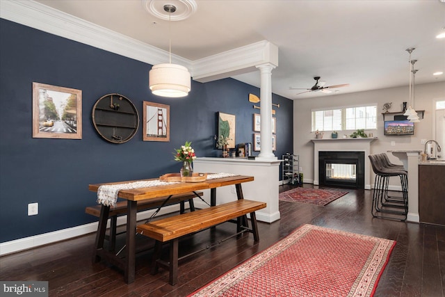 dining space featuring sink, crown molding, ceiling fan, decorative columns, and dark hardwood / wood-style flooring