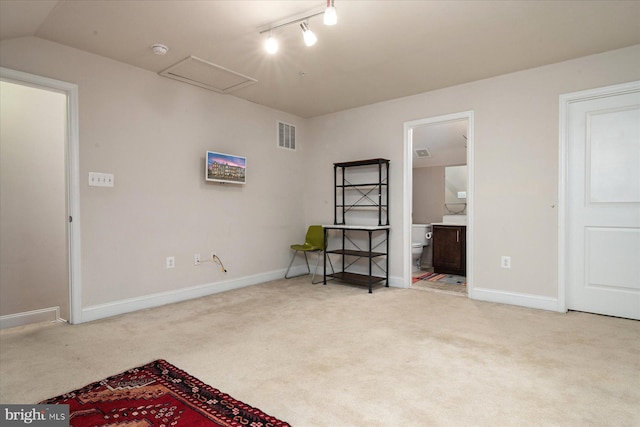 carpeted bedroom with lofted ceiling, track lighting, and ensuite bathroom