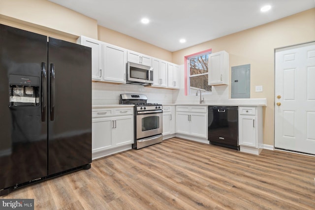 kitchen featuring white cabinetry, electric panel, light wood-type flooring, and black appliances