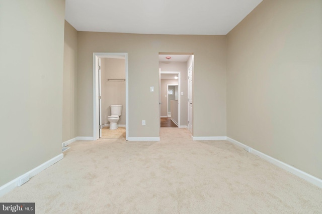 unfurnished bedroom with connected bathroom and light colored carpet