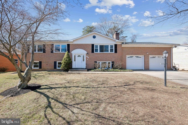 bi-level home with brick siding, a chimney, concrete driveway, an attached garage, and a front yard