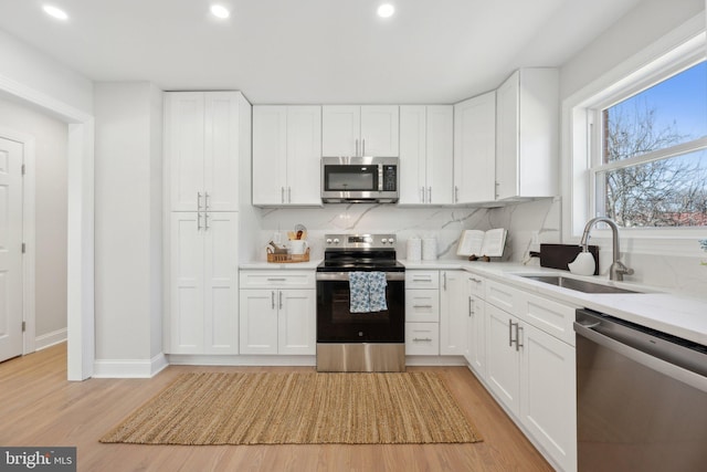 kitchen with tasteful backsplash, white cabinetry, stainless steel appliances, and a sink