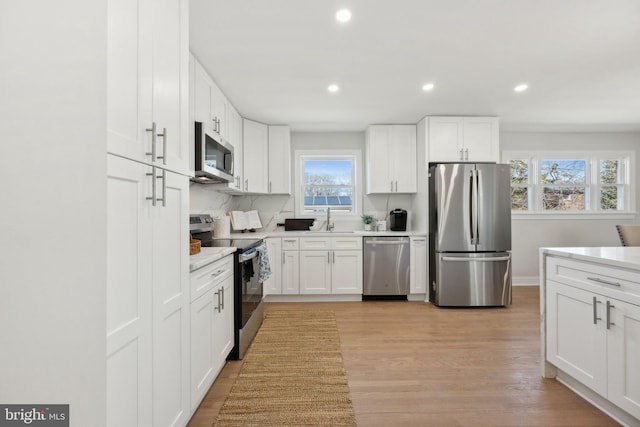 kitchen featuring white cabinets, appliances with stainless steel finishes, light countertops, and a sink