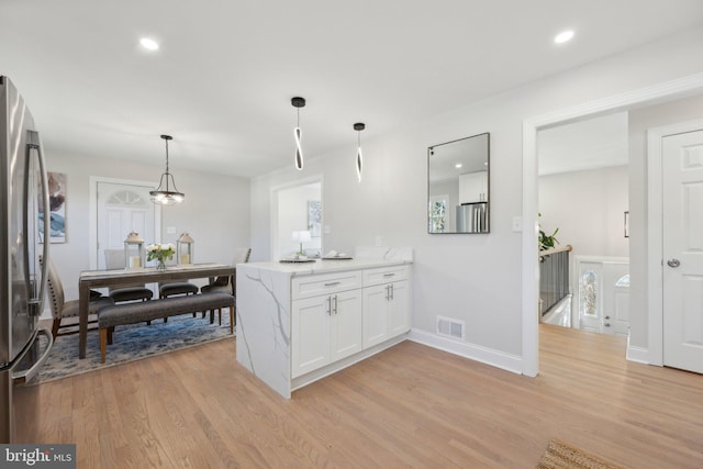 kitchen featuring visible vents, freestanding refrigerator, decorative light fixtures, light countertops, and white cabinetry