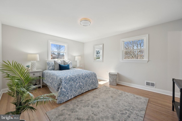 bedroom with baseboards, visible vents, and wood finished floors