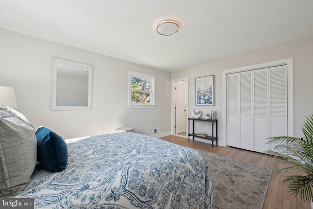 bedroom with a closet, baseboards, and wood finished floors