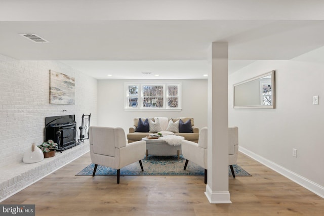 living area with recessed lighting, wood finished floors, visible vents, baseboards, and a wood stove