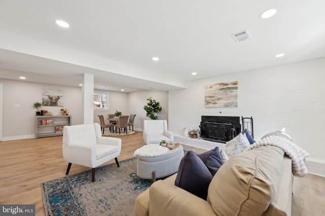 living room featuring recessed lighting, brick wall, visible vents, and light wood finished floors