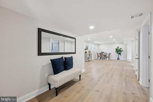 hallway with light wood-style floors, baseboards, and visible vents