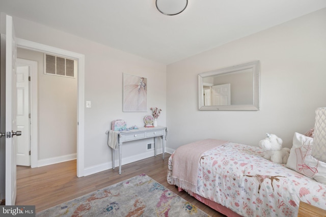 bedroom featuring wood finished floors, visible vents, and baseboards